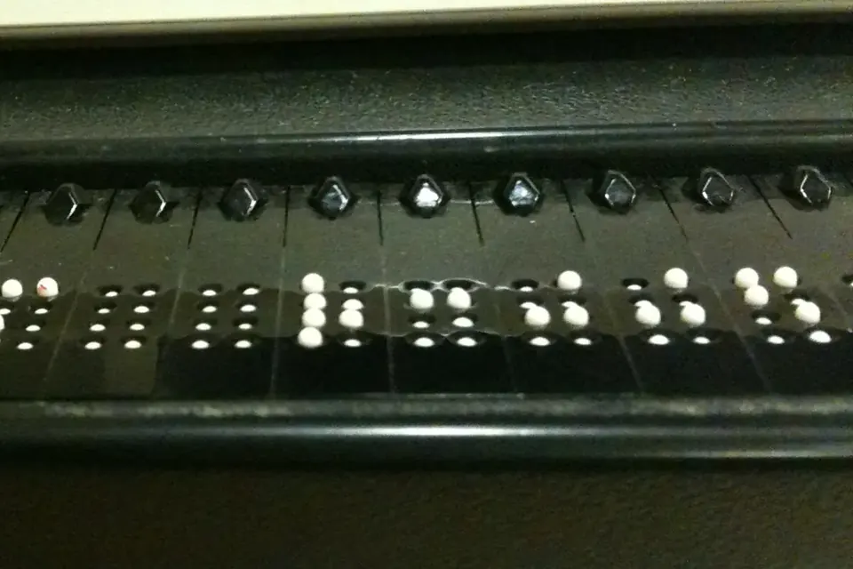 Close-up of a refreshable braille display, with raised white pins forming braille cells below a row of small cursor buttons
