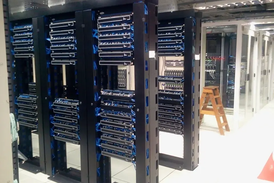 Rows of black server racks with blue cabling in a brightly lit data centre